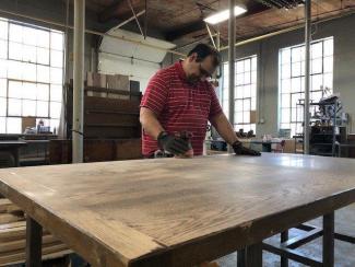 Man working on sanding a table